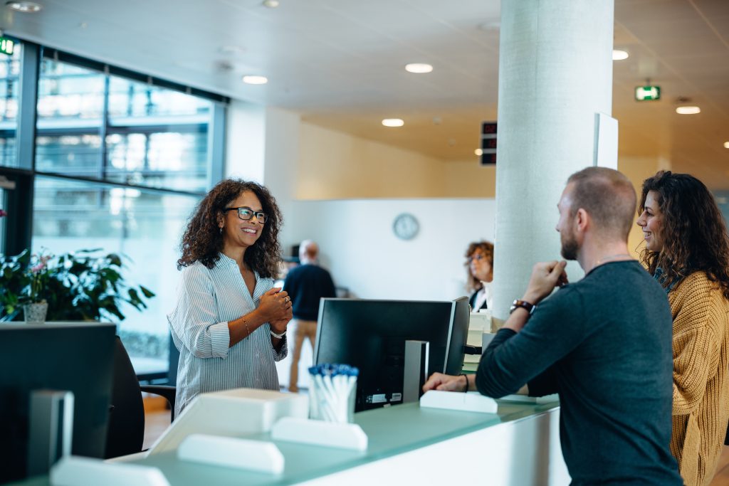 People interacting at a reception desk. Government Record Verification with TimeBinder.